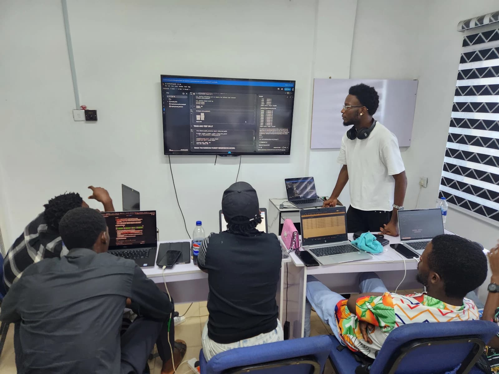 Students at work on their laptops in the lab room, one following a lesson in headphones.