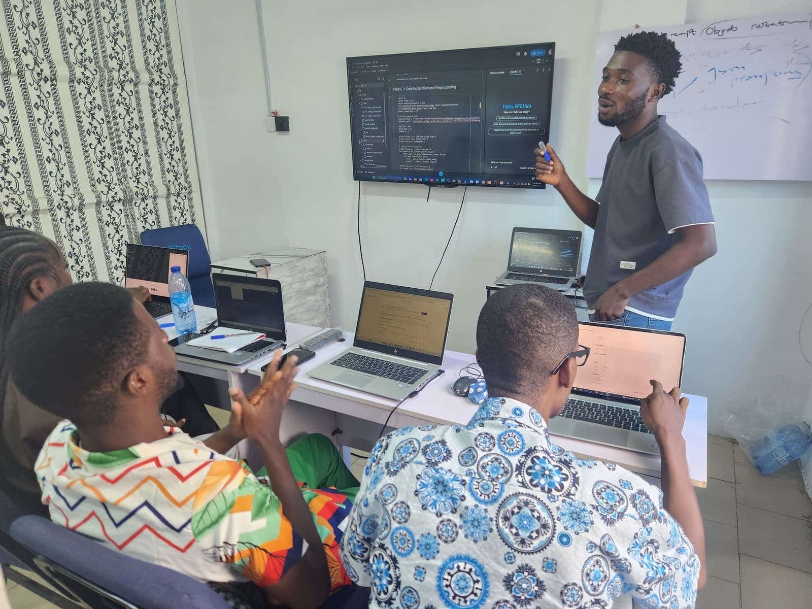 A small group following along on their laptops as an instructor explains code.
